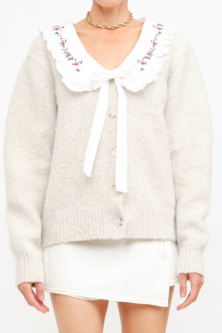 White sweater with a decorative collar and tie on a white background