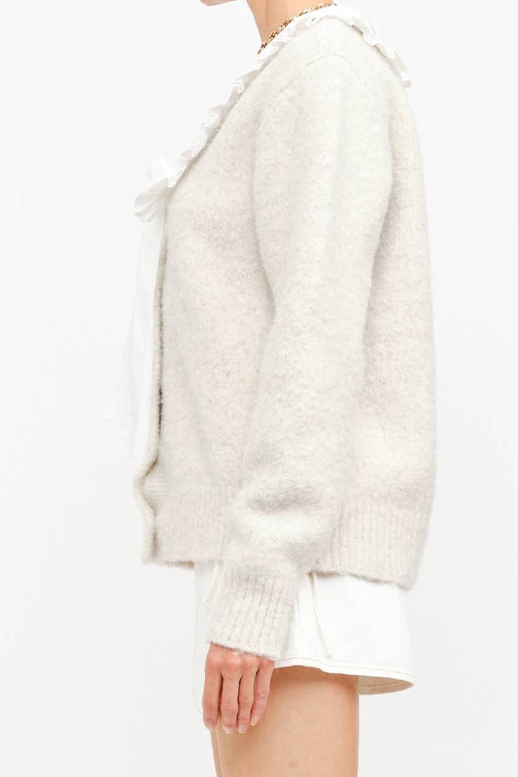 White textured cardigan worn by a person on a white background