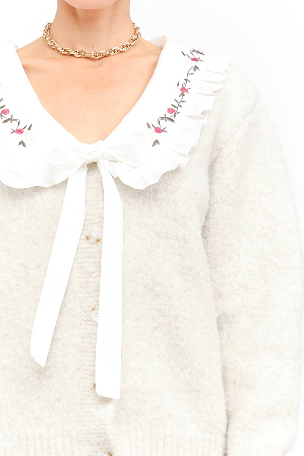 White blouse with floral embroidery and a bow tie on a white background