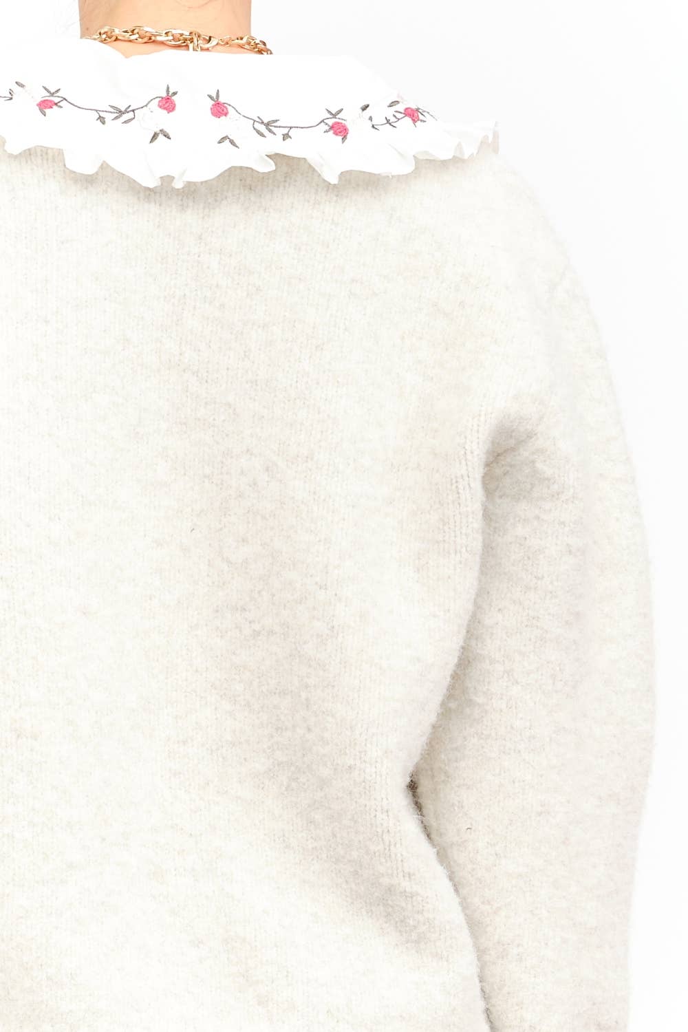 Close-up of a white sweater with floral embroidery on a white background
